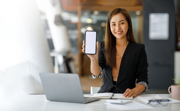 Mockup image of a Young Asia lady show empty smartphone screen with with blank white screen positive expression, smiles casual clothing feeling happiness Mobile phone with white screen in female hand.