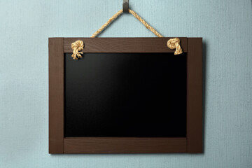 Clean small black chalkboard hanging on light blue wall