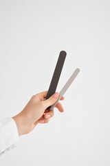 a hand with a nail file on white background with (copy space, vertically)