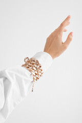 a woman's hand in a shirt with a gold bracelet on a white background, a beautiful palm on a white background (copy space)