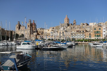 Boats are moored in a small bay in the Maltese city in the sunny summer day