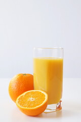 A laconic beautiful picture - a glass of freshly squeezed orange juice, next to which lies a whole orange and half of another orange. This is a good start to the day - a boost of energy and vitamin C