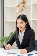 Asian businesswoman sitting at a desk young woman working data analysis charts financial documents with laptop in the office