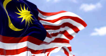 Detail of the national flag of Malaysia waving in the wind on a clear day.