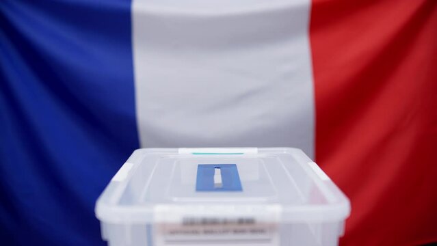French voter throwing a voting ballot into the sealed box, elections in France