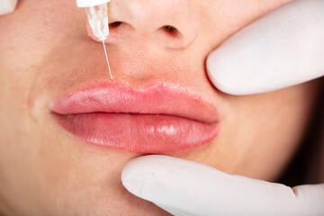 Young lady getting injections for bigger, fuller lips. The woman in the beauty salon. Plastic...
