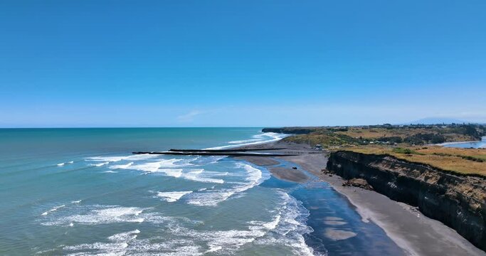 Aerial over eroded sea cliffs and multiple waves on a sweltering day -Patea
