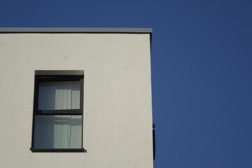 Upper right corner of white house wall with single window, clear blue sky, use: copy space, texture, background (horizontal), Kaiserslautern, RLP, Germany
