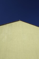 Fototapeta na wymiar Yellow gable under clear blue sky, use: copy space, texture, background (horizontal), Kaiserslautern, RLP, Germany