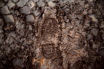 A boot print in the mud close-up. Footprint in the dirt. Bottom of shoes. - obrazy, fototapety, plakaty