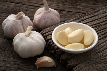 Peeled garlic in a bowl on wooden plate,popular ingredient in cooking due to its strong smell and delicious taste