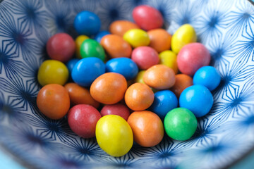 child boy picking multi-colored sweet candies in a bowl close up 