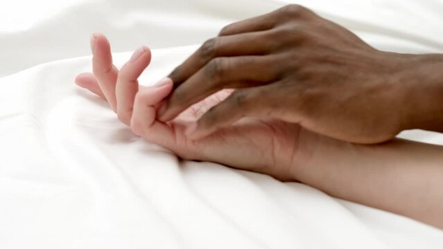 Hands close up multiracial couple african man and caucasian woman romantically touch each other on bed, lovers making Passion love
