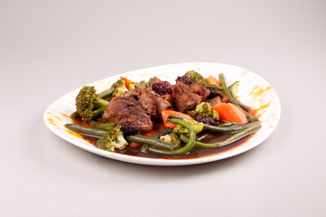duck magret with vegetables on white plate isolated angle view