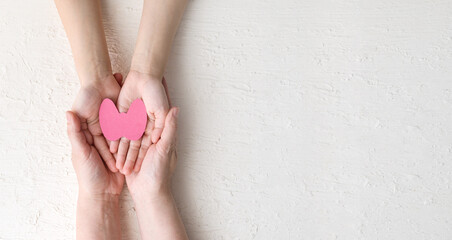World Thyroid Day. women 's and children 's hands hold paper form of the thyroid gland on a white...