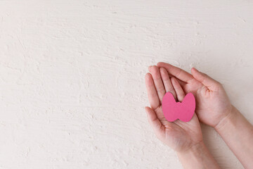 World Thyroid Day. Women's hands hold a paper form of the thyroid gland on a white background. Problems with thyroid. Polycystic disease. World cancer day. copy space. banner