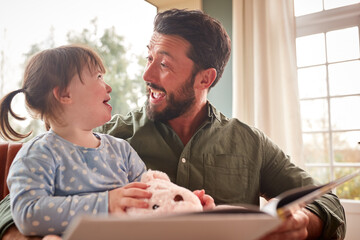 Father With Down Syndrome Daughter Reading Book At Home Together