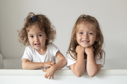 Happy fraternal twins sisters having fun, standing in crib. Happy gitls