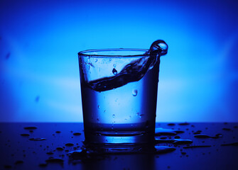 A glass with water at blue background	