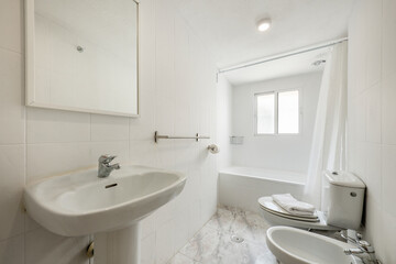 Fototapeta na wymiar Bathroom with shower cabin with curtain, white sink under mirror with fine white wood frame, stoneware floors