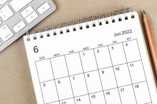 June 2022 desk calendar with pencil on wooden background.