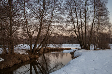 Evening spring landscape. Awakening of nature after winter. Charming evening landscape in early spring. Melting ice and snow.