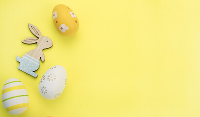 Easter eggs and a rabbit on a yellow background.The concept of a holiday and shopping for Easter. Flat lay. Happy easter greeting card. Copy space