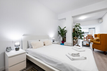 Studio apartment with king size bed, wingback sofas and dining table next to the kitchen