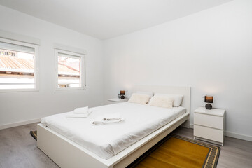 Apartment with king size bed, white side tables and ocher brown carpets