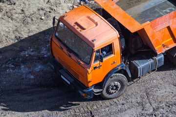 Dump truck unloading soil at construction site.