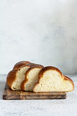 Challah or Hala is a traditional jewish sweet fresh sabbath Braided bread (loaf),  fresh bun (slice of food) on cutting board. Brioche on breakfast table. 