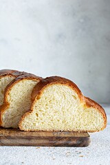 Challah or Hala is a traditional jewish sweet fresh sabbath Braided bread (loaf),  fresh bun (slice of food) on cutting board. Brioche on breakfast table. 