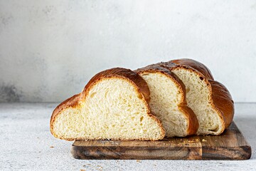 Challah or Hala is a traditional jewish sweet fresh sabbath Braided bread (loaf),  fresh bun (slice of food) on cutting board. Brioche on breakfast table. 