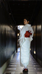 京都、祇園の路地で和服を着て振り返る日本人女性。フルショット - obrazy, fototapety, plakaty