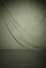 Warm gray draped cloth fabric, a photography studio backdrop which includes the floor area for full...
