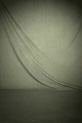 Warm gray draped cloth fabric, a photography studio backdrop which includes the floor area for full...