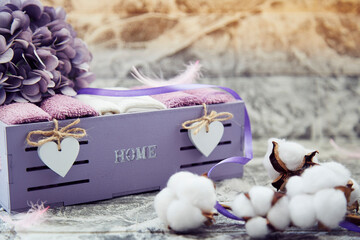 Cozy home concept. Towels in wooden box, cotton and purple flower in home interior.