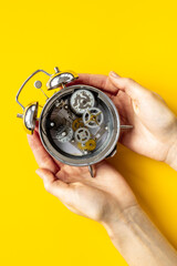 Hands holding alarm clock mechanism with steel gears and wheels close up