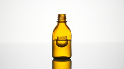 Drop falls into yellow medical bottle with liquid creating splash on white background | Abstract face care serum formulation concept