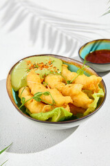 Tempura shrimps with wasabi sauce in ceramic bowl in minimal style. Fried prawns with deep on white background with hard shadow from leaves. Asian food in contemporary style. Modern food.
