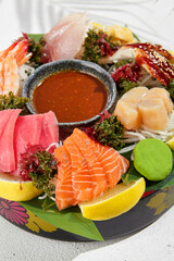 Sashimi set from raw seafood: salmon, tuna, eel, perch, shrimps, sea scallop. Traditional japanesse dish - sashimi on white background. Fresh delicacy on ice with lemon, ginger and sauce.