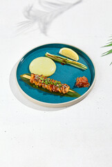 Squid yakitori in ceramic dish on white background. Japanese skewered squid with wasabi sauce. Grilled kalmar on bamboo skewer in asian style. Food menu for izakaya. Summer pan asian menu. © Ryzhkov