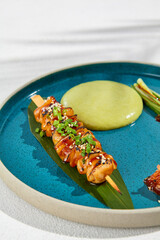 Squid yakitori in ceramic dish on white background. Japanese skewered squid with wasabi sauce. Grilled kalmar on bamboo skewer in asian style. Food menu for izakaya. Summer pan asian menu. © Ryzhkov