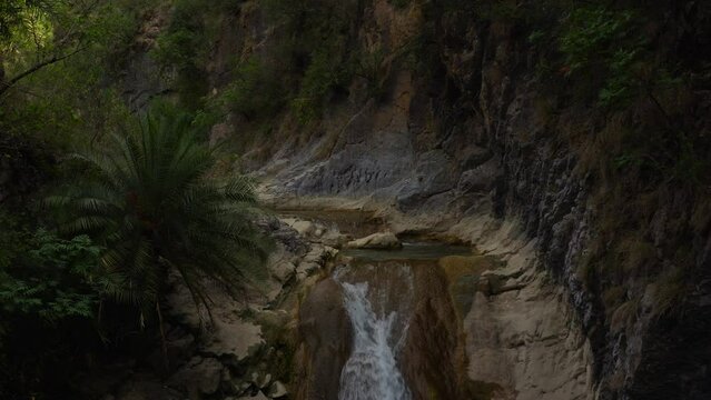Aerial view of a water flowing into the river in between the mountains 