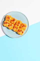Hot sushi roll with cream cheese top and crispy onion. Baked sushi with salmon, cream cheese topped. Hot maki sushi  on coloured background in minimal style.