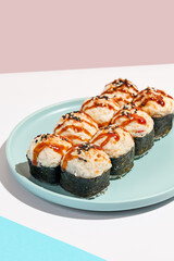 Hot sushi roll with cream cheese top. Baked sushi with seafood and crab, cream cheese topped. Hot maki sushi  on coloured background in minimal style.
