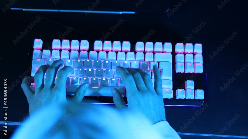 Aufkleber gamer style hacker using led illuminated keyboard. young male hands using keyboard with blue and pur