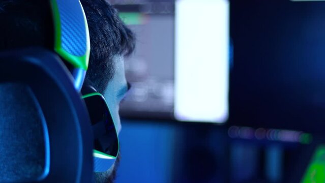 Back View Of A Gamer, Streamer Young Adult In Front Of A Pc Screen With A Green Gamer Headset, 4k Shot.