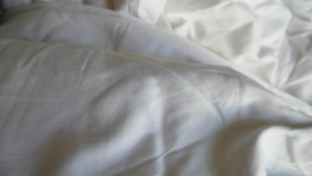 Slow motion cinematic panning to the white clean bed sheets with embroidered hotel world with golden thread
