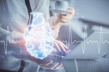 Double exposure of woman hands typing on computer and heart hologram drawing. Education concept.